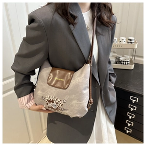 Shoulder bag detail with gray fabric, brown leather flap, and tidal dryness embroidery