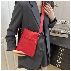 Detail of red lychee textured leather crossbody bag with adjustable nylon shoulder strap