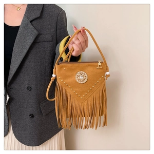 Detail of mustard yellow suede handbag featuring metallic rivets and long fringe tassels