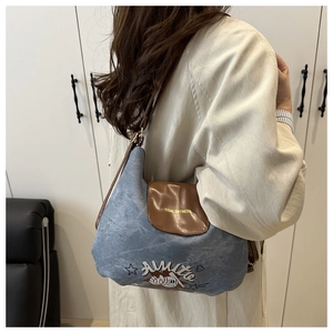 Detailed view of large capacity denim tote bag with brown leather flap and stylish embroidery