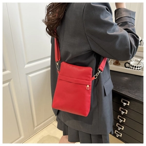 Vertical small square bag in red pebbled leather with wide strap worn by a model