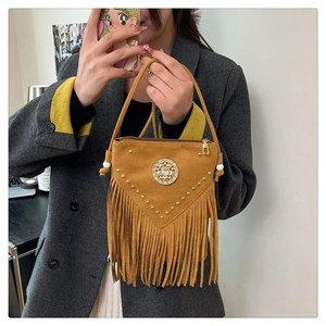Detail view of mustard yellow bohemian bucket bag with golden studs and long fringes