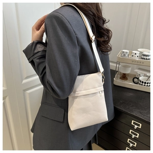 Crossbody wear view of minimalist cream white pebbled leather bag with adjustable strap