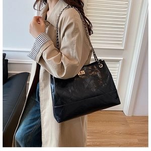 Detailed view of black quilted tote bag with golden chain strap and metal turn-lock