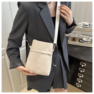 Cream off-white pebbled leather crossbody bag with wide woven strap shown on model