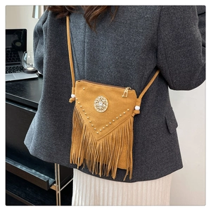 Detail of bohemian suede crossbody bag featuring ginger tassels and metal rivet decor