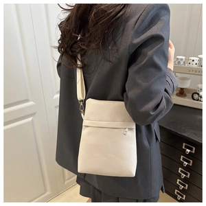 Detail of creamy white litchi pattern leather bag with gold hardware and zipper