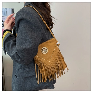Boho mustard suede crossbody bag with metal rivets and long tassels on a model