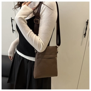 Detail of adjustable nylon strap and golden metal buckle on dark brown crossbody bag