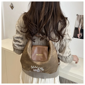 Close-up of a brown textured leather shoulder bag with cartoon fish and Tidal Dryness text
