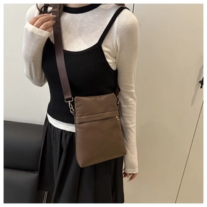 Close-up of brown litchi pattern leather crossbody bag with adjustable wide strap