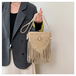 Detail of khaki bohemian saddle bag with golden rivets and long tassel fringe trim