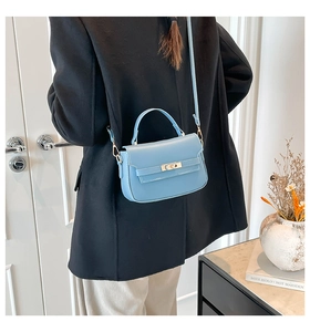 Model wearing a light blue structured crossbody bag showcasing the back view and size