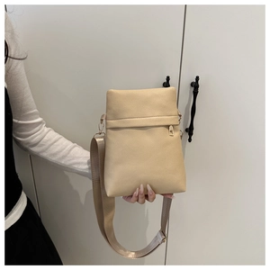 Detailed view of beige lychee texture leather crossbody bag with wide shoulder strap