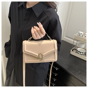 Detail of beige faux leather mini handbag featuring gold clasp and adjustable strap