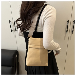 Detail of cream crossbody bag with pebble texture and adjustable wide fabric strap