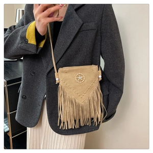 Detail of bohemian khaki tassel bag showing metallic studs and round turquoise inlay decor