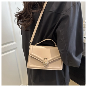 Schicke beige Umhängetasche mit goldenem Drehverschluss an einem weiblichen Model