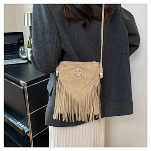 Detail of khaki suede crossbody bag with fringe, gold rivets, and crystal embellishment