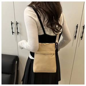 Detail of beige textured leather crossbody bag showing lychee grain and wide fabric strap