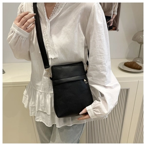 Close-up of black pebble leather crossbody phone bag worn over a white vintage blouse