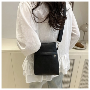 Detail of black pebbled PU leather crossbody bag with gold hardware and wide woven strap