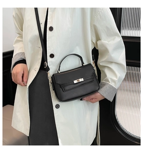 Detail of black leather square handbag with golden twist lock and adjustable shoulder strap