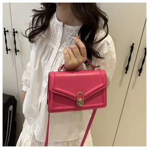 Detail of fuchsia leather square bag with gold oval buckle and top handle grip