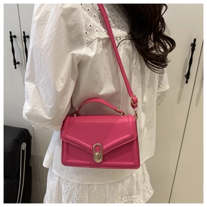 Detail of rose red crossbody bag with golden oval twist lock on elegant lace outfit