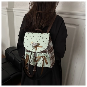 Detail of vintage mint green backpack featuring brown plaid side panels and ribbon bow