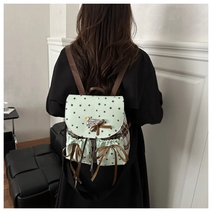 Detail view of mint green canvas backpack with stars and brown bow on female model