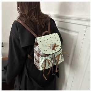 Detail of star print and plaid canvas backpack with brown ribbon bow accents