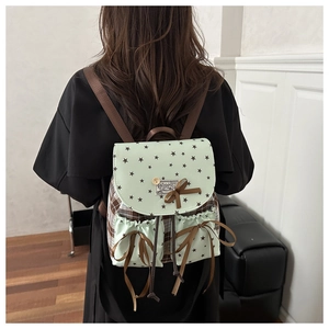 Detail of mint green and brown star-patterned backpack with ribbon bows and check panel