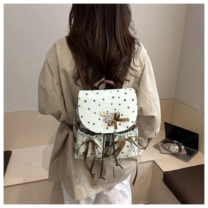 Detail of mint green school backpack featuring star patterns and brown silk bow accents