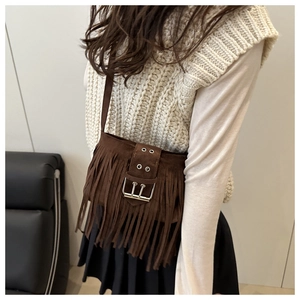 Gros plan du sac à bandoulière en daim marron avec franges et grosse boucle métallique rétro