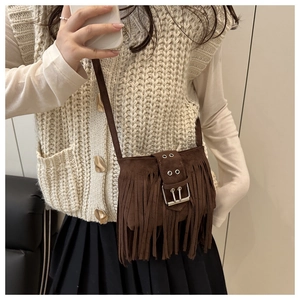 Détail du sac bandoulière en daim marron foncé avec de longues franges et boucle
