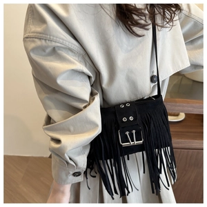 Détail du sac bandoulière en daim noir avec de longues franges et une boucle argentée