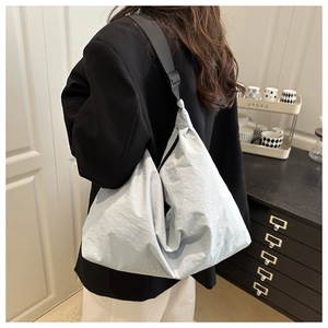 Rear view of a light blue oversized nylon crossbody hobo bag with a black wide strap