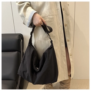 Close-up of black nylon hobo tote bag with wide strap and silver metal zipper detail