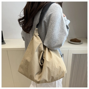 Nylon pillow tote bag with black wide strap shown in a minimalist lifestyle setting