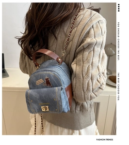 Detail of blue denim mini bag with cat embroidery and elegant gold twist lock hardware