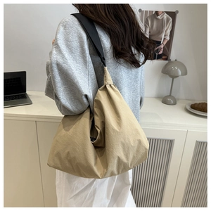 Detailed view of the khaki nylon tote bag with wide black strap in a modern setting
