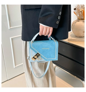 Detail of the light blue suede handbag featuring a gold lock closure and chain strap