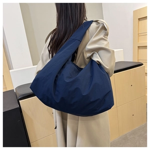 Große dunkelblaue Beuteltasche am Modell zeigt das geräumige Volumen und den Fall