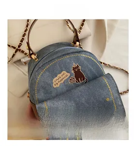 Detail of mini denim cat bag with brown leather handle and gold twist lock closure