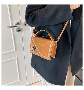 Detail of caramel suede crossbody bag with geometric stitching and metal clasp on coat