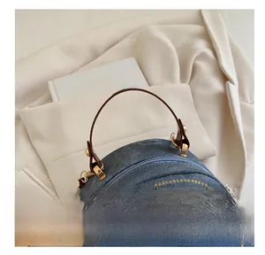 Detail of blue denim mini backpack featuring cat pattern and leather top handles