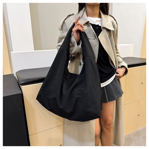 Minimalistische schwarze Tote Bag mit entspannter Silhouette am Modell getragen