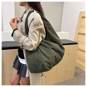 Olivgrüne Hobo-Tasche in Oversize-Passform mit beigem Trenchcoat in modernem Interieur