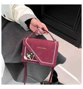 Detail of burgundy suede handbag with V-shaped white stitching and gold clasp lock